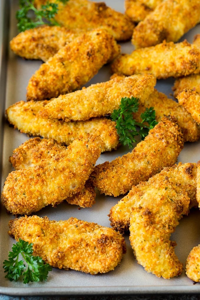 Baked chicken tenders on a sheet pan, garnished with parsley.