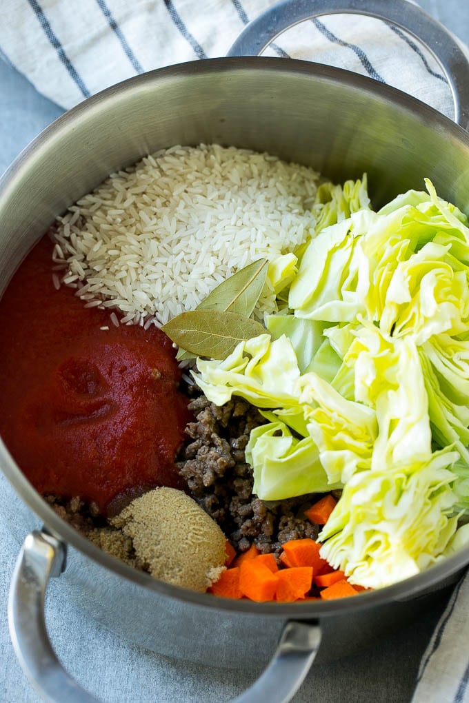 Ingredients for cabbage roll soup including beef, cabbage, vegetables and spices, all in a soup pot.