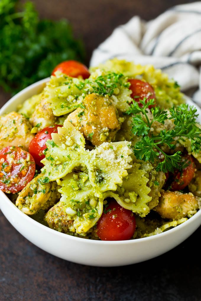A bowl of chicken pesto pasta garnished with parsley.
