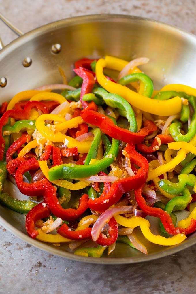 Sauteed bell peppers and onions in a pan.