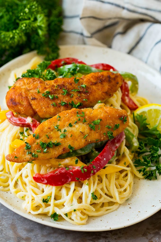 A plate of chicken scampi with angel hair pasta and red bell peppers.