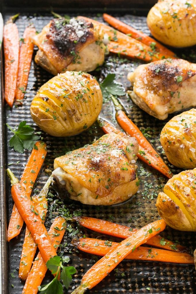 A sheet pan with maple dijon chicken, hasselback potatoes and roasted carrots.