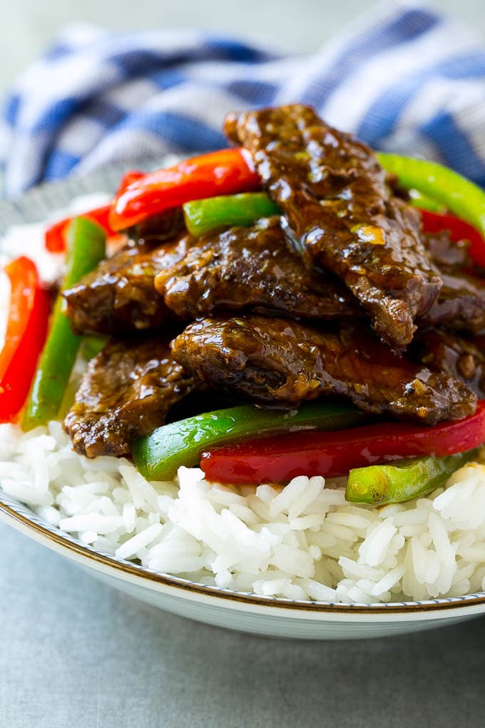A bowl of rice topped with pepper steak stir fry.