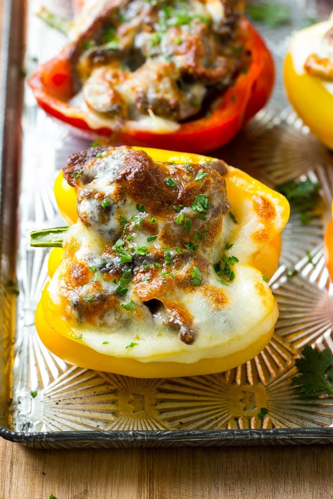 Philly cheesesteak stuffed peppers topped with melted cheese on a sheet pan.