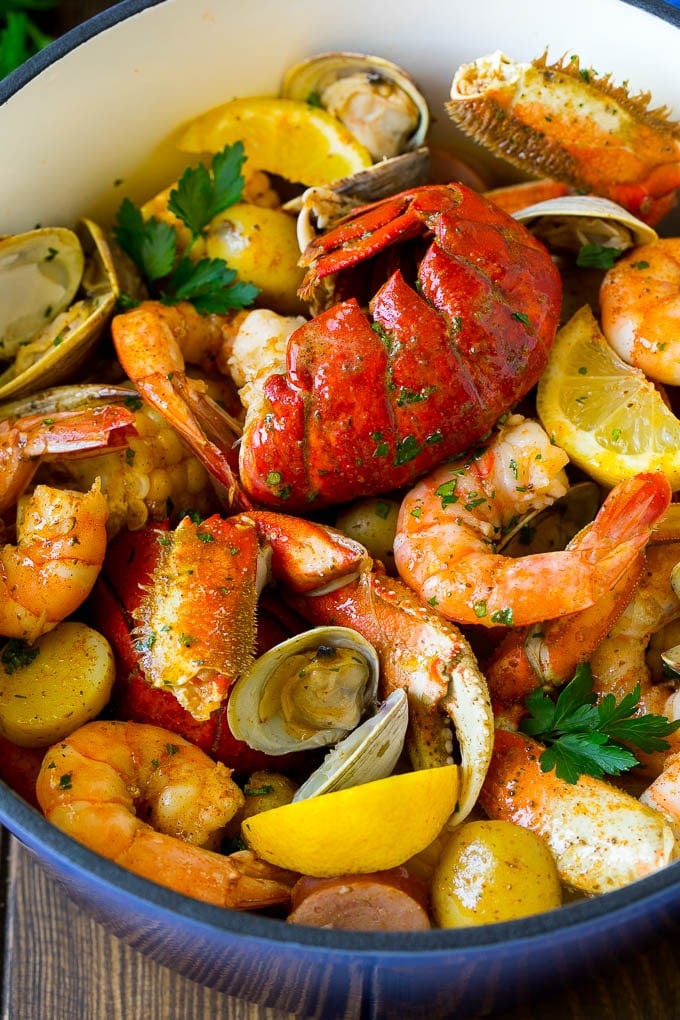A pot of seafood boil with lobster, shrimp, corn and potatoes.
